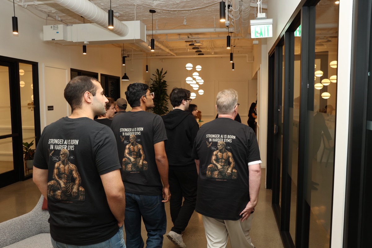 A group of team members in matching t-shirts walking together down an office hallway.